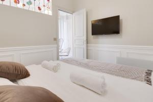 a white bedroom with a bed and a flat screen tv at GuestReady - Lovely flat in Central Paris near Notre-Dame in Paris