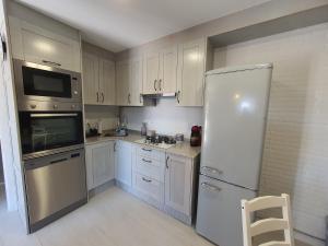 a kitchen with white cabinets and a white refrigerator at Casa Jalecha in Muxia