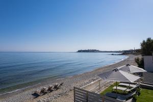 a beach with chairs and umbrellas and the ocean at Deux Paradis, a BeachFront Retreat, By ThinkVilla in Rethymno Town