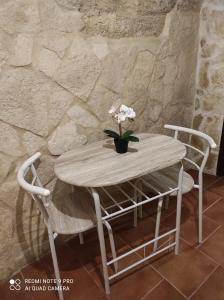 una mesa de madera con 2 sillas y un jarrón de flores en Il Tufo D'amare appartamento affitti brevi, en Rutigliano