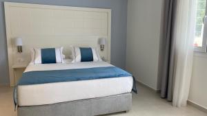 a bedroom with a bed with blue and white pillows at Acrotel Lily Ann Village in Nikiti