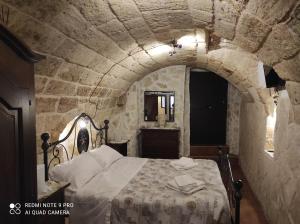 1 dormitorio con 1 cama en una pared de piedra en Il Tufo D'amare appartamento affitti brevi, en Rutigliano