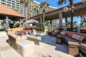 un patio con sofás, mesas y palmeras en Gorgeous San Luis Condo Amazing Pool Amenities Ocean Views From 2 Balconies, en Galveston