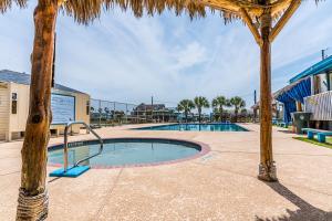 a swimming pool with palm trees in a resort at SUNNY DAZE Walk to Beach 2 Decks Pet Friendly Has a Mini Bar in Galveston