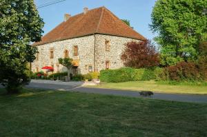 a dog walking in front of a large stone building at Au Grand Fête, B&B à la campagne in Le Fête