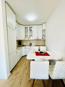 une cuisine avec des placards blancs et une table et des chaises blanches dans l'établissement 4 llullat - City Center Apartment, à Pristina