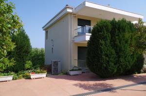 a white house with a bush in front of it at Anesis Luxury Apartments in Skala Sotiros