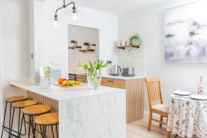 a kitchen with a white counter top and wooden stools at 32 Evesham Road - By Luxury Apartment in Cheltenham