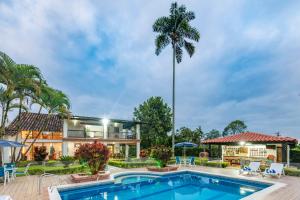 una casa con una piscina y una palmera en Casa Campestre La Habana, en Armenia