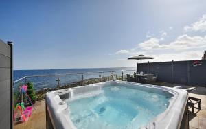 a hot tub on a patio overlooking the ocean at Pod 1, Sinclair bay lodges in Keiss