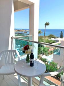 a table with two wine glasses and flowers on a balcony at Saradari Beach Hotel - Adults Only in Hersonissos