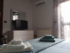 um quarto com toalhas numa cama com televisão em GRETA'S HOUSE em Comitini