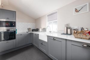 a kitchen with white counter tops and appliances at The Cottage, The Loch Ness Cottage Collection in Inverness