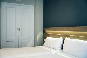 a bedroom with a white bed with a wooden headboard at Hotel Alda Estación Pontevedra in Pontevedra