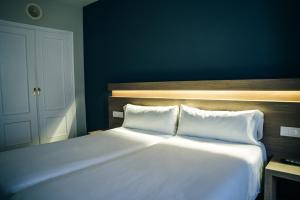 a white bed with two pillows in a bedroom at Hotel Alda Estación Pontevedra in Pontevedra