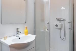 La salle de bains blanche est pourvue d'un lavabo et d'une douche. dans l'établissement GuestReady - Yazdah Flat 3, à Porto