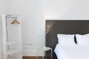 a white bed sitting in a bedroom next to a white wall at GuestReady - Ayres Studio w Balcony Garden in Porto
