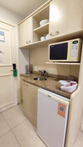 a small kitchen with a sink and a microwave at Jurerê Beach Village in Florianópolis