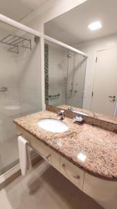 uma casa de banho com um lavatório e um espelho grande em Jurerê Beach Village em Florianópolis
