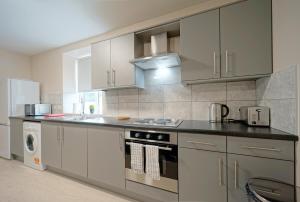 a kitchen with white cabinets and a stove top oven at Alpha Lofts, Huddersfield in Huddersfield