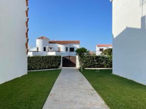 a walkway through a yard with a white house at Sa Posta De Sol in Cala en Blanes