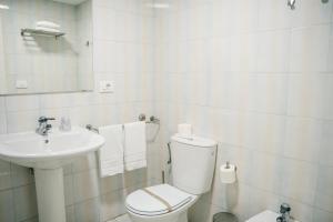 Un baño blanco con inodoro y lavabo. en Hotel Alda Estación Pontevedra, en Pontevedra