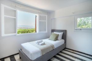 a white bedroom with a bed with two windows at Phaedrus Living Sea View Villa Aegina in Perdhika +17 photos
