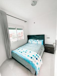 1 dormitorio con cama con sábanas azules y ventana en Hôtel champ élysée, en Saidia 