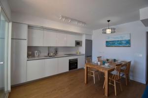 kuchnia z białymi szafkami i stołem z krzesłami w obiekcie MAGNOLIO APARTMENT CALACEITE w mieście Torrox Costa