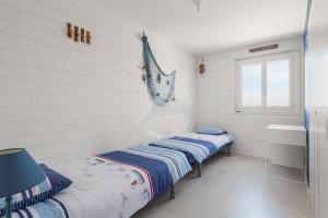 twee bedden in een kamer met witte muren en een raam bij AS21932 - Appartement P3 magnifique Vue Mer en dernier étage sur le Front de Mer in Le Grau-du-Roi