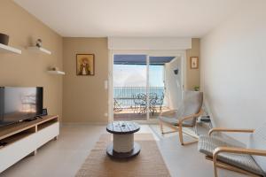 een woonkamer met een televisie en een tafel en stoelen bij AS21932 - Appartement P3 magnifique Vue Mer en dernier étage sur le Front de Mer in Le Grau-du-Roi