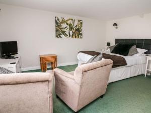 a bedroom with a bed and two chairs at Triangle Inn Coachouse in Rhayader