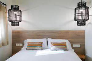 a bedroom with a white bed with two pillows and chandeliers at Apartaments la Rambla - Arbequina - 6 persones in Cornudella