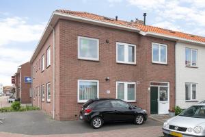 a black car parked in front of a brick house at Hello Zeeland - Vakantiehuis Noordstraat 32 in Zoutelande