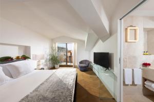 a white room with a bed and a tv at Hotel Palazzo Manfredi – Small Luxury Hotels of the World in Rome
