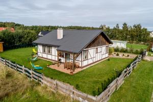 a house with a black roof on a green field at Domki u Olgi in Rusinowo