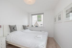 a white bedroom with a bed and a window at Hello Zeeland - Vakantiehuis Noordstraat 32 in Zoutelande