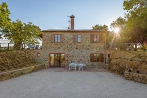 een stenen huis met een tafel ervoor bij Villa Il Cipresso in Sinalunga