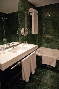 a bathroom with a sink and a tub with towels at Aravaca Village Hotel in Madrid