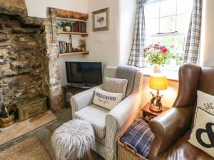 a living room with a chair and a television at Otters Holt in Great Asby