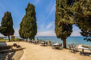 a row of trees and tables and chairs next to the water at Villa Valdepian Apartments in Savudrija