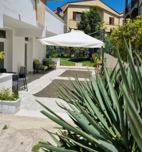 a patio with a white umbrella and some plants at B&B Kamalei in Tropea