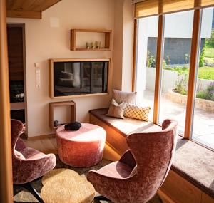 sala de estar con sillas, mesa y TV en Alpenchalet Vils Tirol en Vils