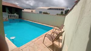 einen Pool mit zwei Stühlen neben einem Gebäude in der Unterkunft Pousada Aliens in São Thomé das Letras