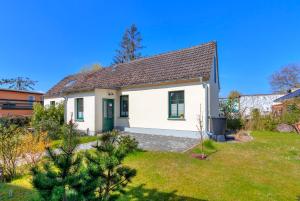 ein weißes Haus mit grüner Tür im Hof in der Unterkunft Gartenoase Ahlbeck -01 in Ahlbeck