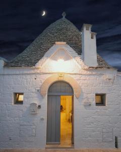 a white church with a lit up doorway at night at Trullo Antica Bellezza in Alberobello