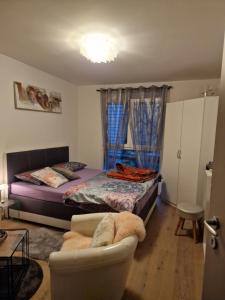 ein Schlafzimmer mit einem Bett, einem Sofa und einem Stuhl in der Unterkunft Chambre aux bord de l'Areuse in Areuse