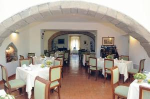 a restaurant with white tables and chairs and an archway at Hotel Urbano V in Montefiascone
