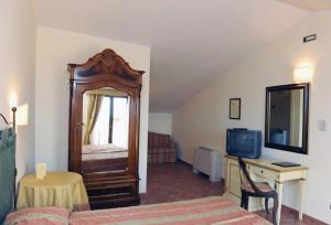 a bedroom with a bed and a desk with a television at Hotel Urbano V in Montefiascone