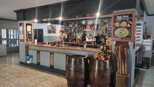 a bar with a clock and two metal barrels at Hostal Restaurante Solaire in Castañar de Ibor